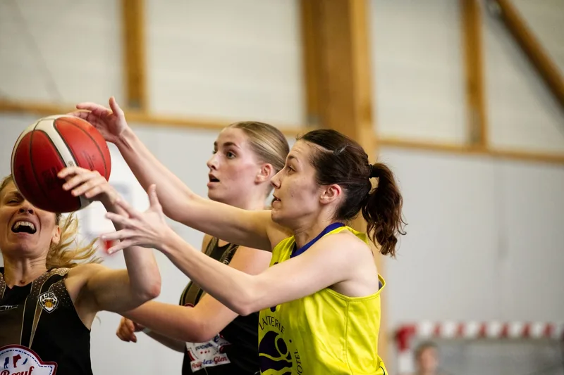 Close-up of women basketball players in a competitive game, reaching for a ball indoors. (stock photo via Pexels)